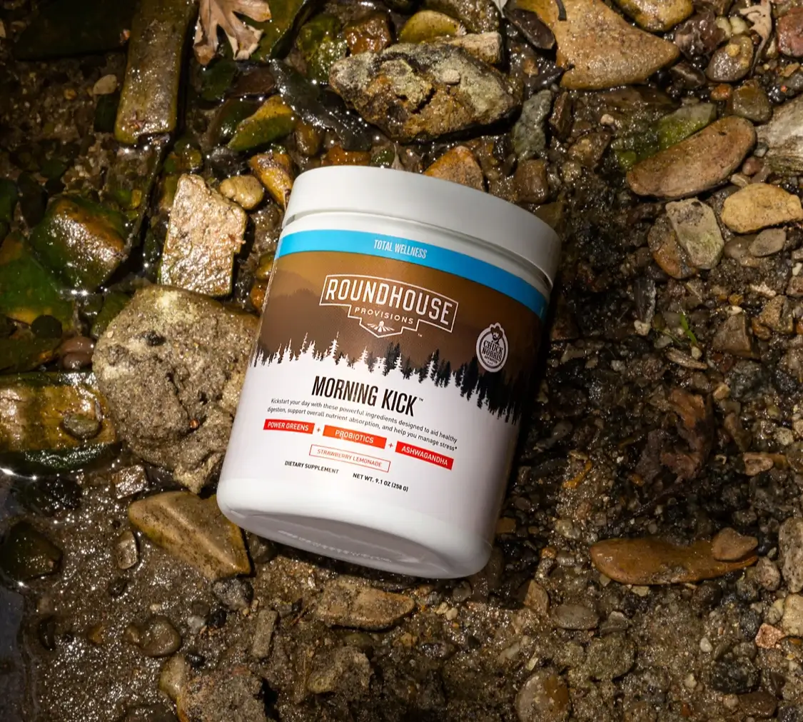 Image of Morning Kick container on a bed of wet rocks.