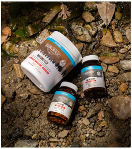 Photo of Morning Kick container plus two other smaller supplement bottles from Roundhouse Provisions all laying face up on a bed of rocks.